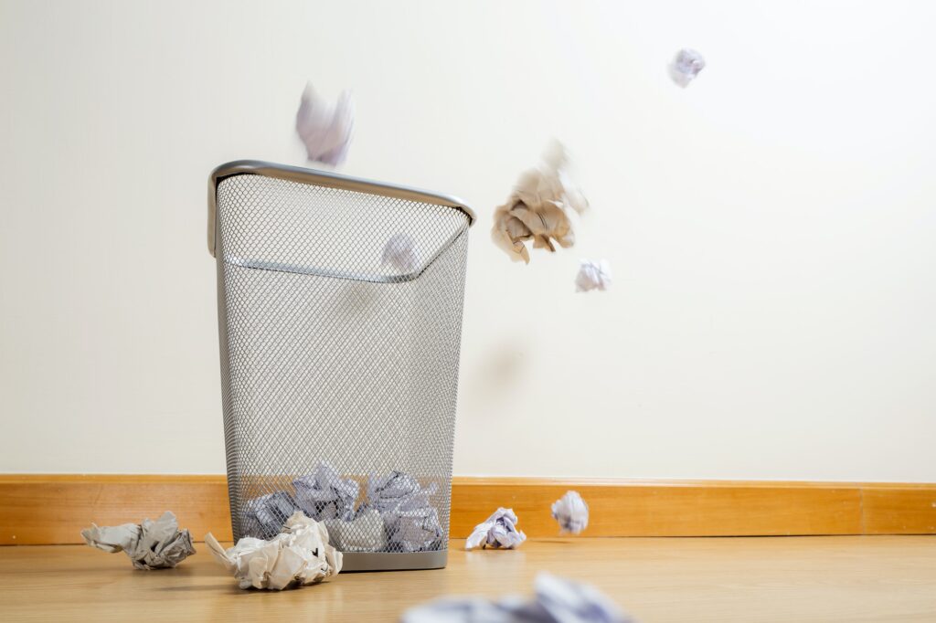 Silver trash bin and crumpled papers