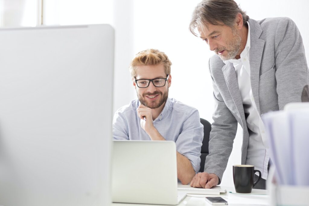 Two businessmen with laptop at desk
