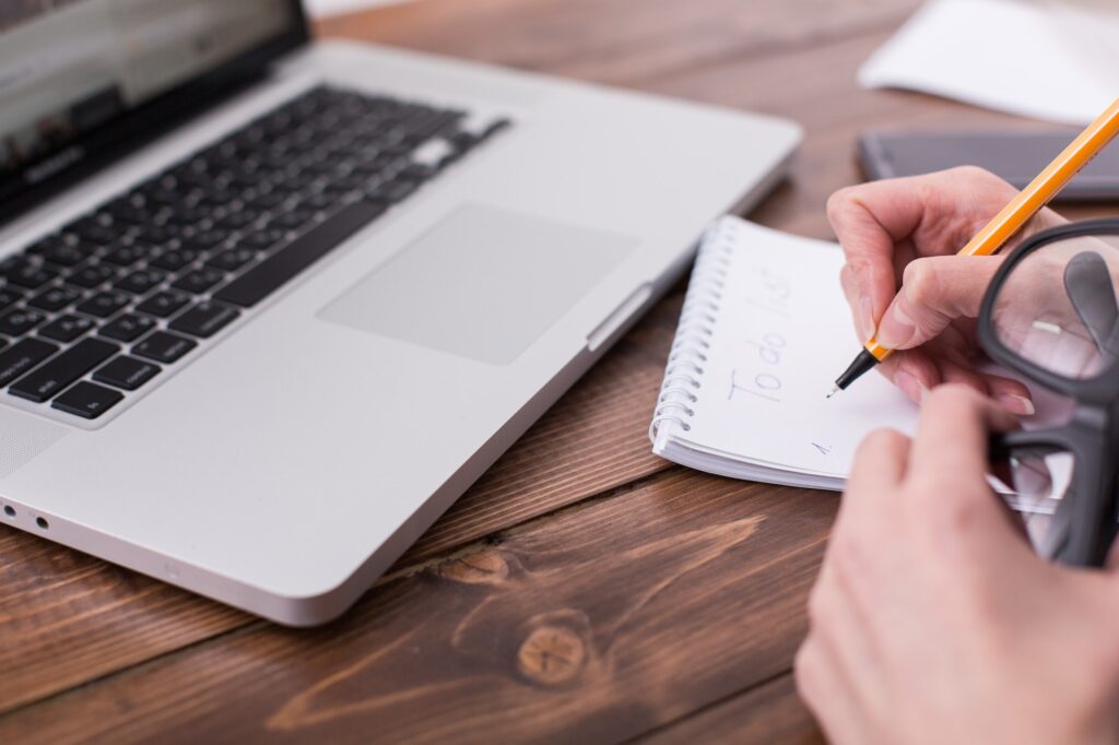 Coaching Online Leeromgeving 4 Young woman with laptop writes a to-do list in a notebook. Businesswoman writing a to do list while