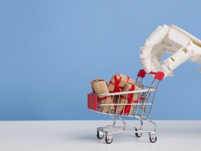 Robot hand with shopping cart full of gift boxes, blue background