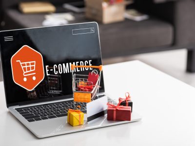 Toy gift boxes and credit card on laptop with e-commerce lettering on table