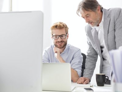Two businessmen with laptop at desk